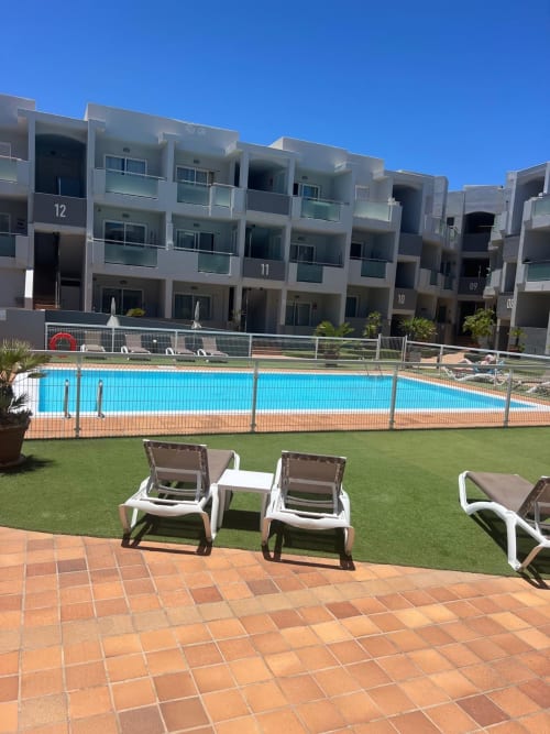 Apartamento con vista a piscina FTV Holidays Homes en Corralejo con tumbonas, piscina vallada y edificios de arquitectura moderna