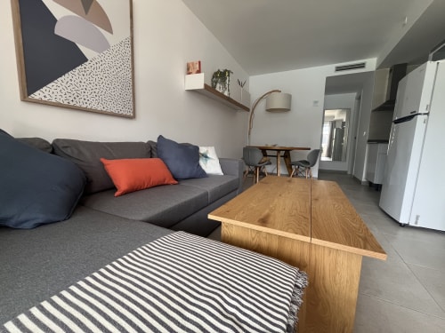 Salón moderno con sofá gris, mesa de comedor de madera y alfombra a rayas en FTV Holidays Homes, Corralejo