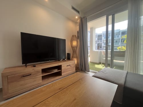 Moderno salón con Smart TV, muebles de madera y balcón con vistas a Corralejo en FTV Holidays Homes