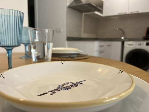Mesa de comedor elegantemente presentada en FTV Holidays Homes Corralejo, con platos blancos decorados y cristalería de diseño moderno