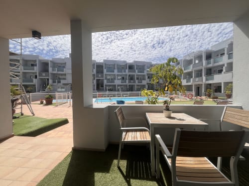 Patio sombreado con mesa de comedor con vistas a la piscina y patio interior en FTV Holidays Homes, Corralejo