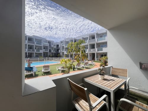 Vista del balcón del apartamento Corralejo Sol y Sal con piscina, tumbonas y edificios blancos en FTV Holidays Homes