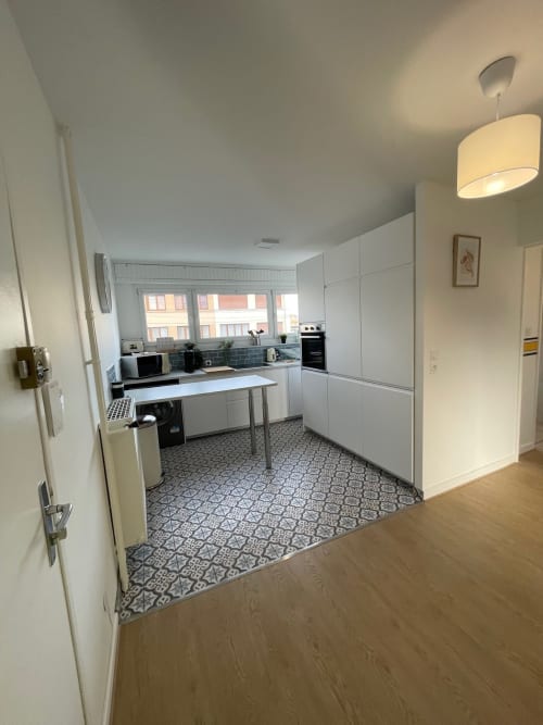 Cuisine moderne blanche avec dosseret en carrelage bleu, électroménagers inox et sol à motifs chez Mattbnb Metz