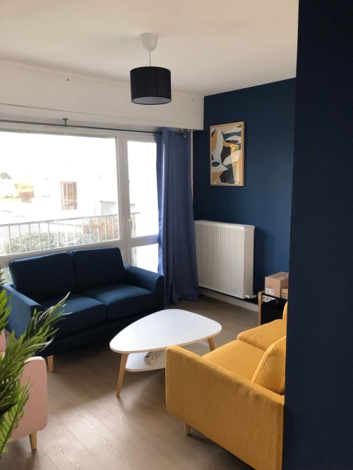 Salon moderne de l'hôtel de Metz avec canapé bleu marine, fauteuil jaune, table basse blanche et vue sur la ville
