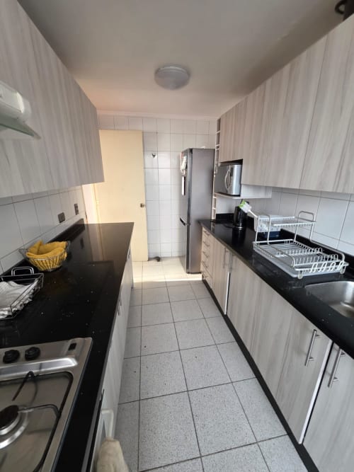 Cocina moderna del apartamento Tamarugo en Your Place Spa, Antofagasta, con electrodomésticos de acero inoxidable y encimeras negras