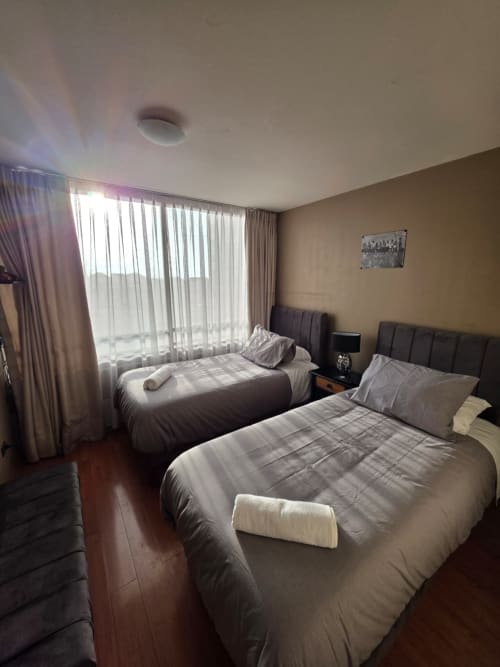 Camas gemelas en habitación moderna de Your Place Spa, Antofagasta con vista al mar y ventanales de piso a techo