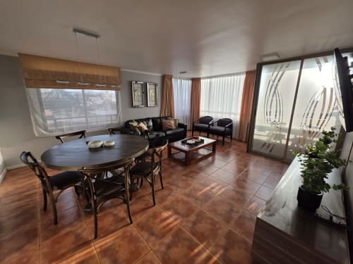 Moderna sala de estar con mesa de comedor, sofá de cuero negro y vistas al mar en Your Place Spa, Antofagasta