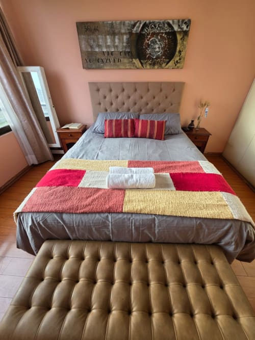 Habitación con cabecera capitonada beige, ropa de cama a rayas coloridas, cama individual y mesitas de noche en hotel Your Place Spa, Antofagasta