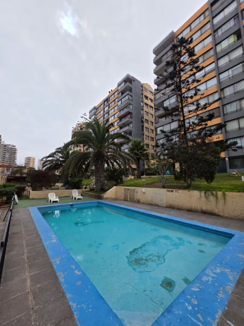 Piscina vacía del hotel balneario Your Place Spa en Antofagasta con modernos edificios de apartamentos y palmeras
