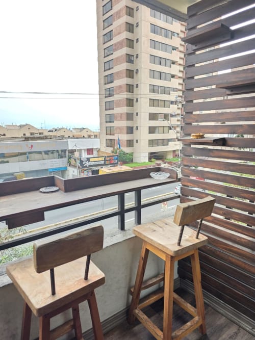Terraza moderna en la azotea del hotel Your Place Spa en Antofagasta con muebles de madera, mamparas de lamas y vistas a la ciudad