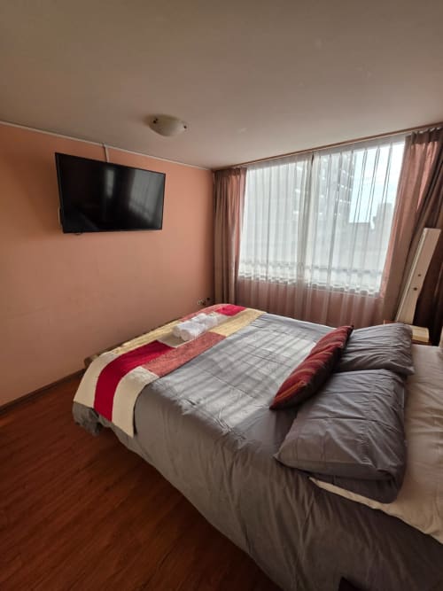 Dormitorio moderno en el hotel Your Place Spa de Antofagasta con TV de pared, vistas al mar y camas cómodas