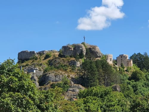 Rocky hilltop with cross and ruins of Hôtel Du Rocher in Le Caylar, France