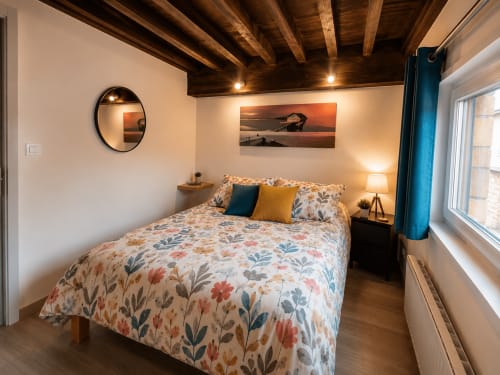 Chambre cosy de la Systeo B&B à Châtillon-sur-Chalaronne avec literie à fleurs, poutres apparentes et vue sur la ville