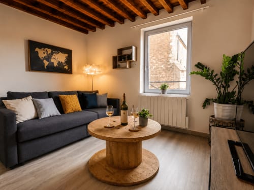 Appartement cosy à la Systeo B&B à Châtillon-sur-Chalaronne avec canapé sombre, table en bois et vue sur la ville