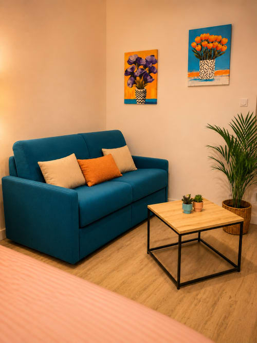 Canapé bleu-vert avec coussins orange dans le séjour de l'appartement Systeo à Mâcon, France