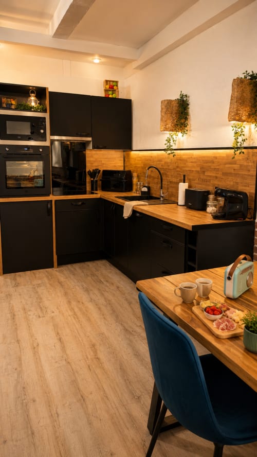 Cuisine moderne aux armoires noires et plan de travail en bois, appartement Systeo, Mâcon
