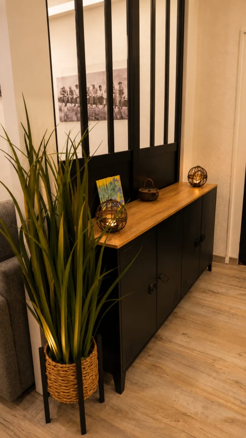 Entrée moderne de l'appartement Systeo Mâcon avec meuble noir, comptoir bois, sphères décoratives et plante en pot