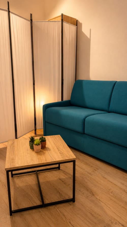 Espace de vie moderne à l'appartement Systeo à Mâcon avec canapé bleu-vert, table en bois et séparateur lumineux