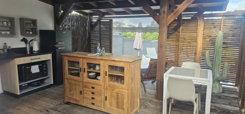 Kitchenette de bungalow moderne avec meubles en bois, électroménagers noirs et vue sur la piscine de Habitation Villa Les Cassias