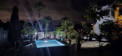 Piscine illuminée la nuit entourée de palmiers à l'Habitation Villa Les Cassias, boutique hôtel à Petit Bourg, Guadeloupe