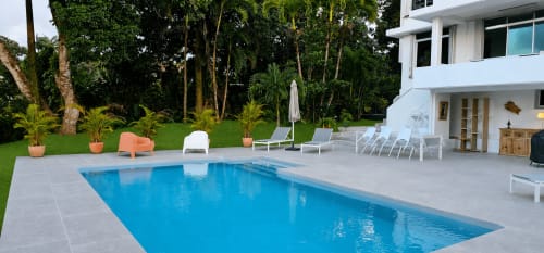 Zone piscine de la Villa Les Cassias avec transats, jardin tropical et bâtiment blanc moderne à Petit-Bourg, Guadeloupe