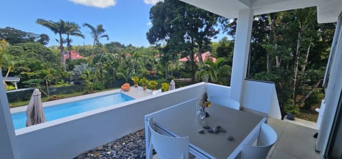 Salle de bains moderne à la Villa Les Cassias avec vue sur la piscine et les jardins tropicaux à Petit-Bourg, Guadeloupe
