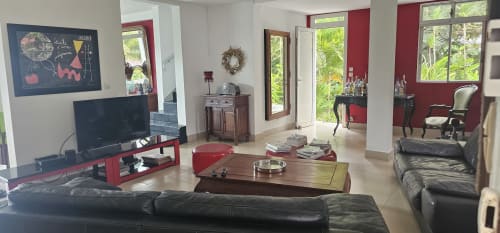 Salon moderne à Habitation Villa Les Cassias en Guadeloupe, accents bordeaux, sièges en cuir noir et style tropical