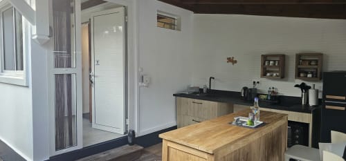 Kitchenette moderne au Bungalow Néo de l'Habitation Villa Les Cassias, Guadeloupe, avec îlot en bois, plan de travail noir