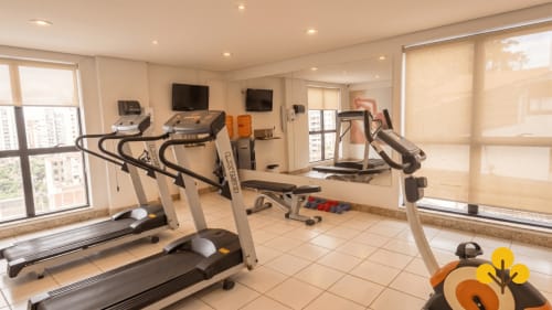 Academia moderna com esteiras e bicicletas ergométricas com vista do horizonte de Goiânia no hotel apartamento Wellington Rodovalho
