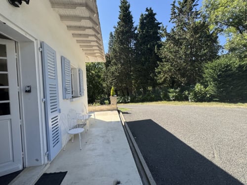 Patio du studio à la Domaine de Bize Mirepoix avec volets blancs, vue sur le jardin et cour en gravier en Ariège