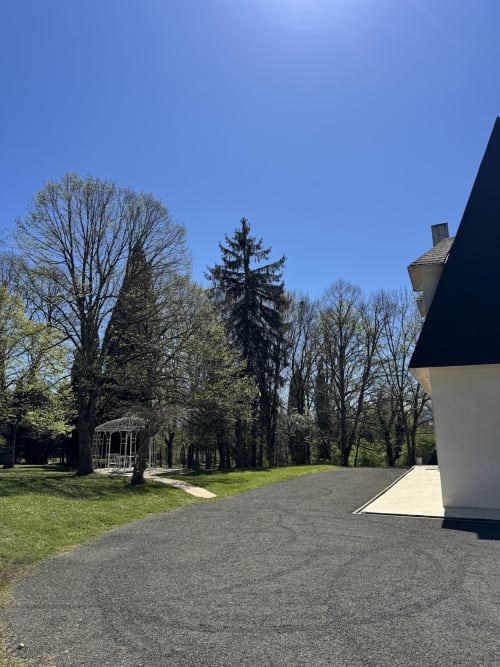 Jardin du Domaine de Bize Mirepoix avec pelouse soignée, arbres matures, gazébo et éléments architecturaux modernes sous ciel dégagé