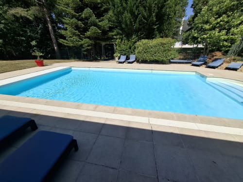 Piscine bleu cristal avec transats au Domaine de Bize à Mirepoix, Ariège, entourée d'arbres verdoyants