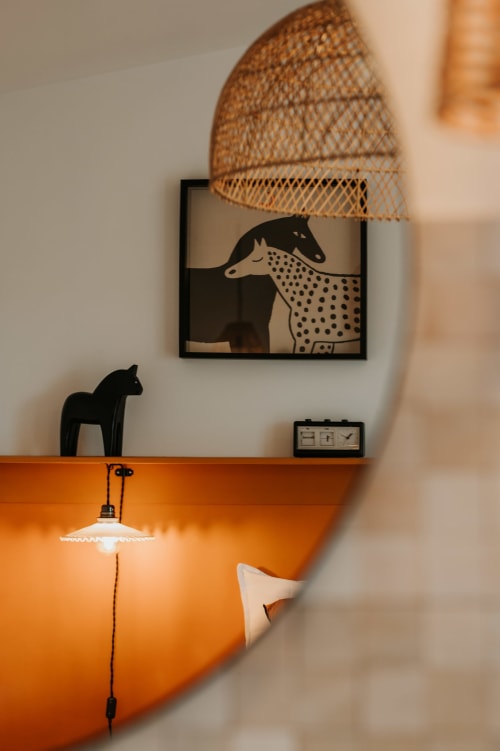 Décoration chaleureuse aux écuries du bout du monde : œuvres animalières, luminaire suspendu en tissage et mur d'accent orange à Landunvez
