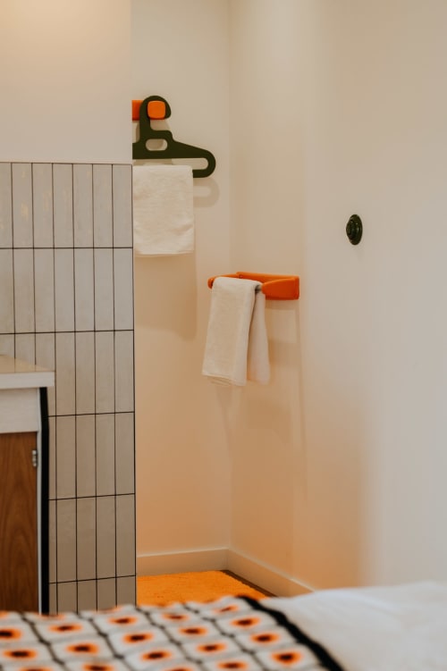 Salle de bains moderne avec porte-serviettes vert et orange, murs carrelés, sol à motifs aux Écuries du bout du monde, Landunvez