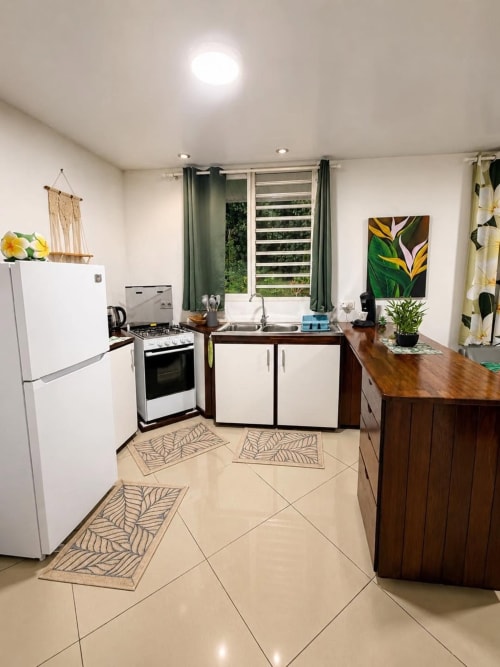 Cuisine moderne et lumineuse à la villa du Maatea Tropical Lodge avec électroménagers blancs, placards en bois, carrelage et ambiance tropicale