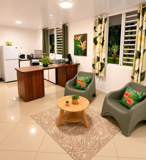 Villa du Maatea Tropical Lodge avec salon, kitchenette, fauteuils verts, rideaux fleuris et vue sur mer