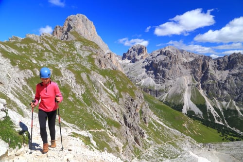 Hiker in pink jacket on alpine trail with dramatic Dolomite peaks near Puget-Théniers, France