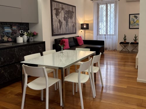 Zona living open-plan moderna a Domus Caecilia Roma con tavolo da pranzo bianco, divano nero e arredamento contemporaneo