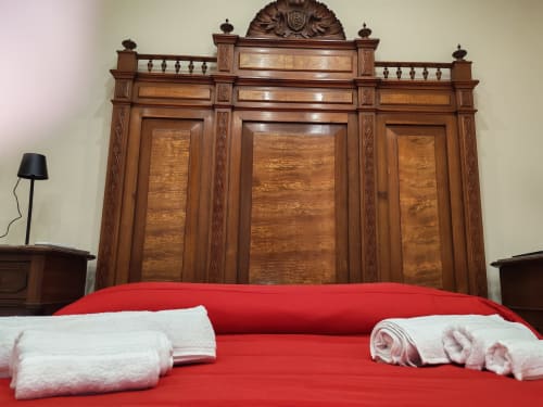 Elegante guardaroba in legno con biancheria rossa e asciugamani bianchi nella suite Queen Deluxe di Sicily Confort Maison