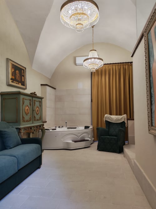 Bagno termale lussuoso presso Sicily Confort Maison con vasca idromassaggio, lampadario e vista sul giardino a Linguaglossa