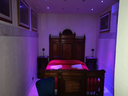 Lussuosa camera da letto di Sicily Confort Maison con letto in legno decorato, illuminazione ambientale viola e comfort moderni