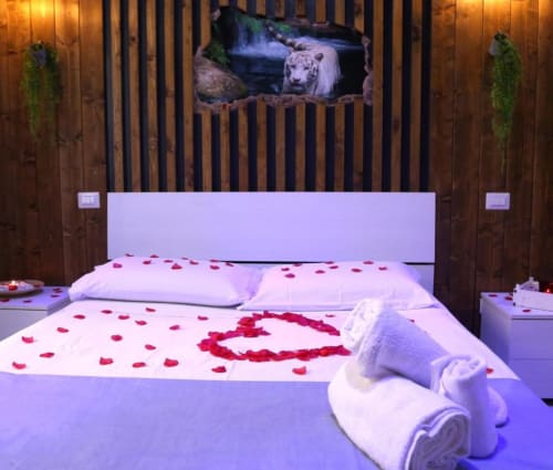 Suite Magnolia presso The Flower Garden con romantici petali di rosa sul letto e tigre bianca nel murale della testata, Castellammare di