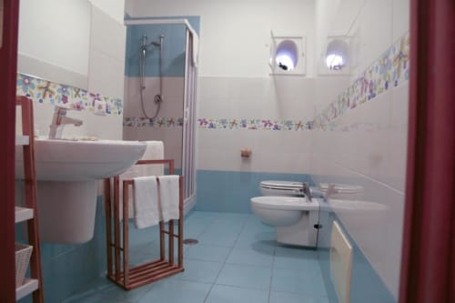 Bagno moderno della Flower Garden B&B a Castellammare di Stabia con piastrelle blu e bianche, lavandino, toilet, doccia