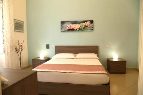 Camera tripla Ortensia presso The Flower Garden B&B a Castellammare di Stabia con letto in legno, opera d'arte loto rosa e menta