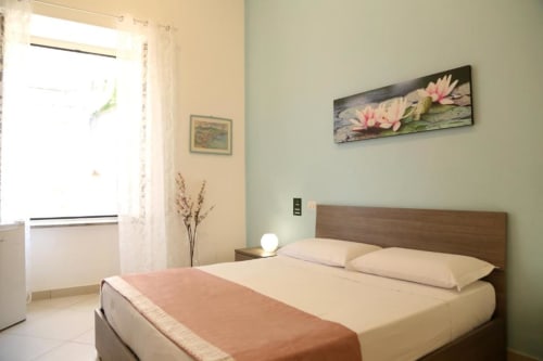 Camera luminosa presso The Flower Garden B&B con letto matrimoniale, testiera in legno, opere d'arte floreale e finestra con vista sulla città