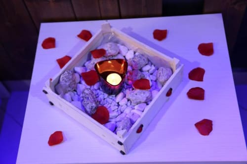 Allestimento romantico con candele, petali di rosa rossa e pietre in scatola bianca presso la Suite Magnolia di The Flower Garden, Castellammare di