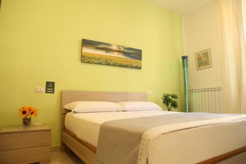 Camera da letto gialla luminosa con letto matrimoniale, quadri di girasoli e vista sulla città presso The Flower Garden B&B a Castellammare di Stabia