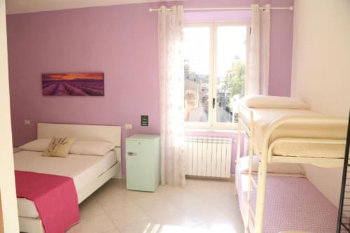 Camera quadrupla Lavanda al The Flower Garden B&B di Castellammare di Stabia: pareti rosa, due letti, vista balcone, design moderno
