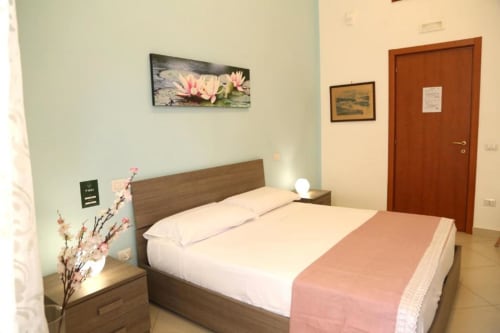Camera tripla Ortensia presso The Flower Garden B&B a Castellammare di Stabia, con letto in legno, biancheria rosa e dettagli verde menta
