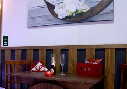 Tavolo romantico nella Suite Magnolia del The Flower Garden B&B con champagne, calici, decorazioni a cuore rosso e legno